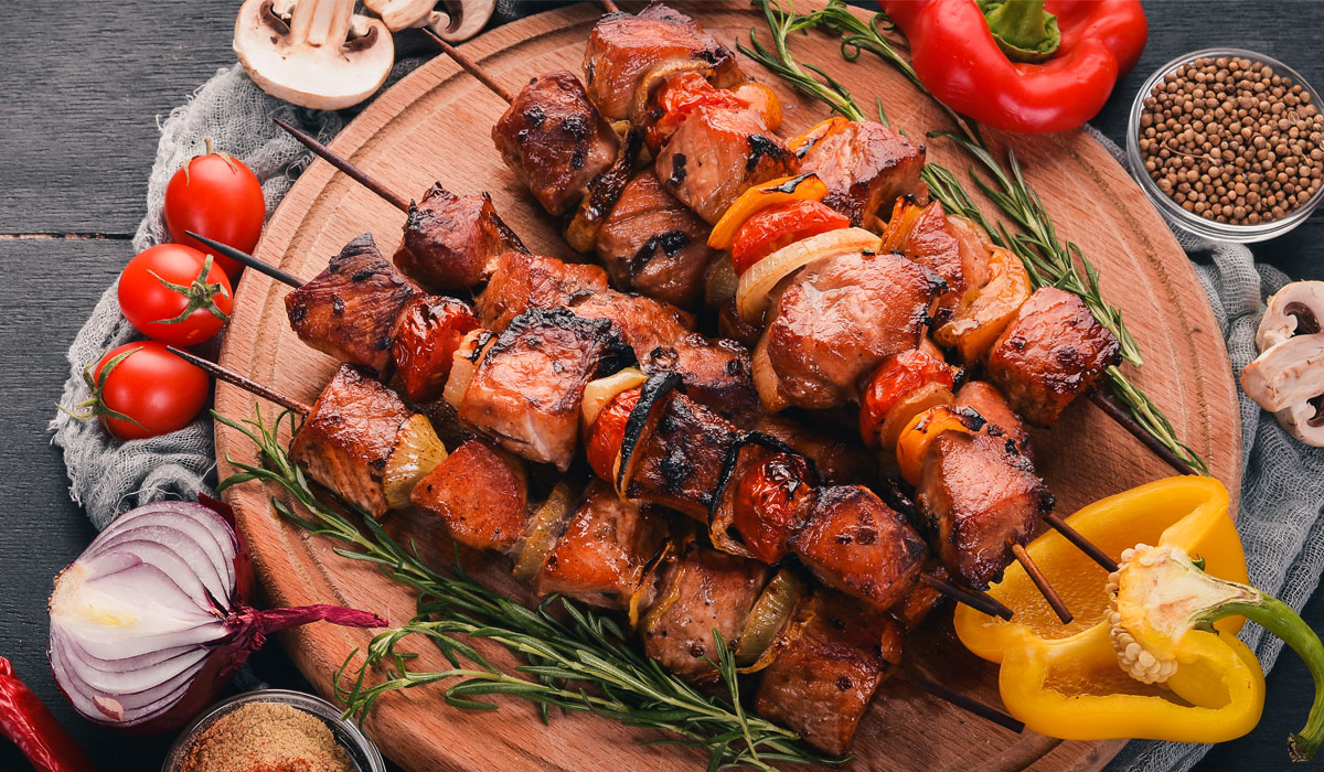 Shish Kebab On Skewers With Onion On A Black Wooden Table.