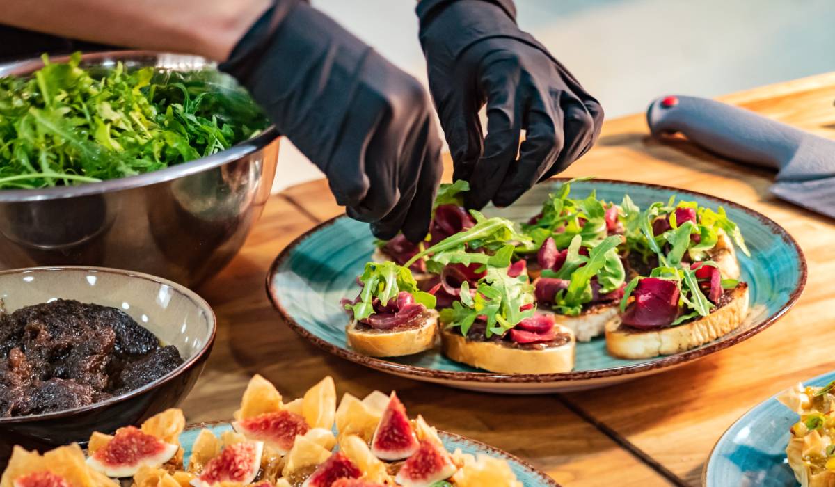 Catering plate being prepared by a chef with gloves.